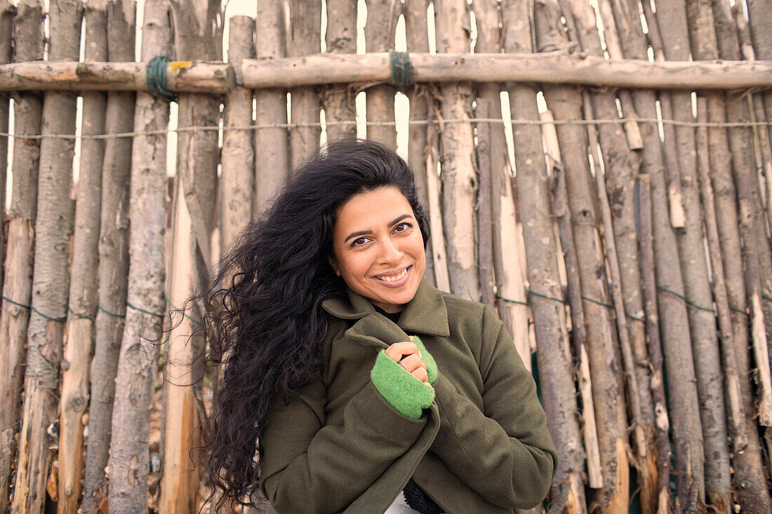 Happy woman in winter coat at wood fence