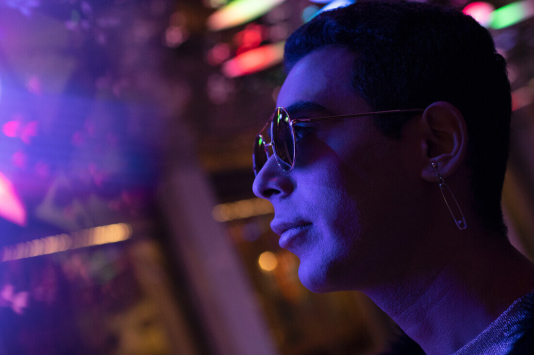 Young man in sunglasses under neon light