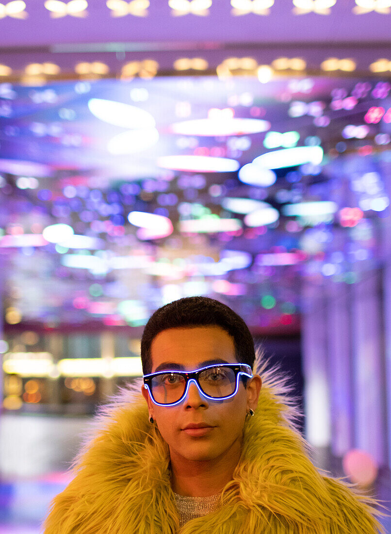 Young man in feather boa and neon glasses