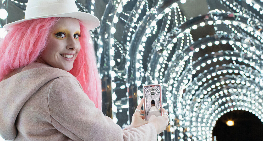Woman with pink hair photographing arch lights