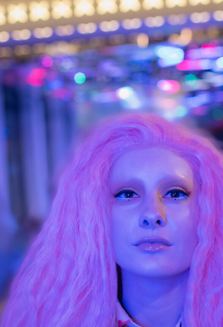 Confident woman with pink hair under neon light