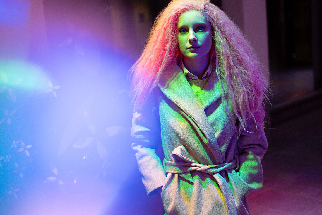 Woman with pink hair in wool coat in neon light