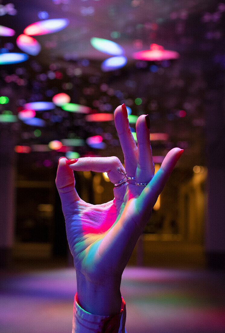 Woman gesturing okay with hand under neon lights