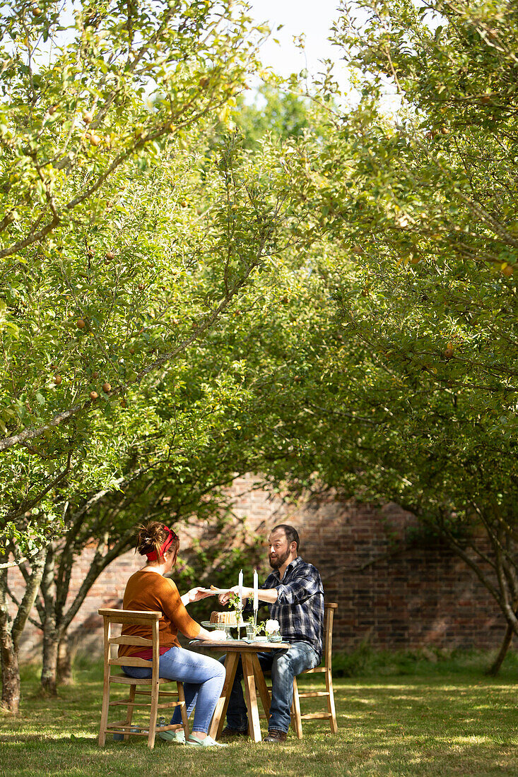 Couple enjoying cake at sunny summer garden table