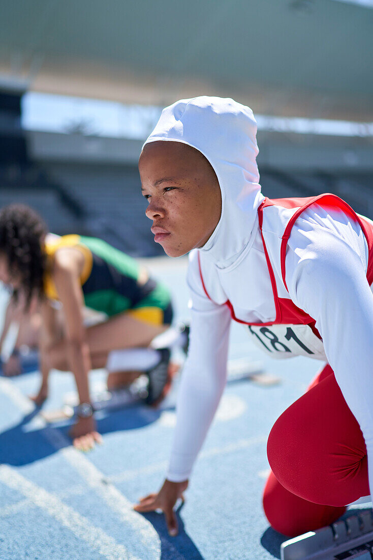 Focused athlete in hijab at start block