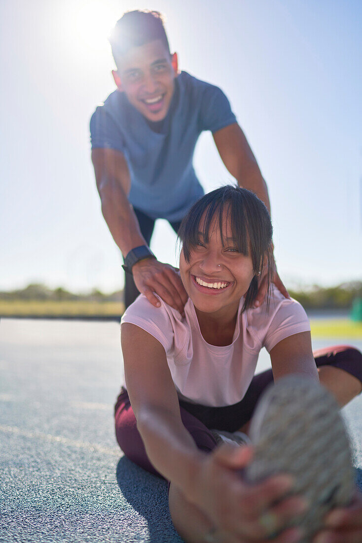 Happy confident young runners stretching on sports track