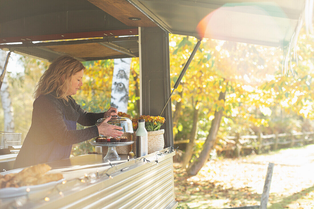 Female food truck owner arranging pastries in autumn park