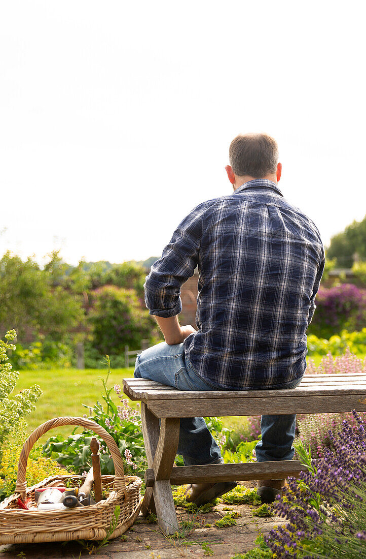 Man taking a break from gardening on bench in garden