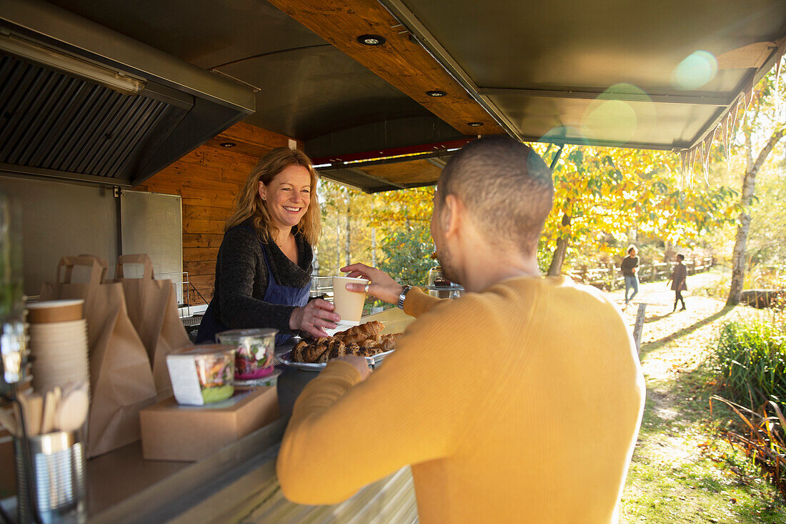 Friendly food cart owner serving coffee to customer