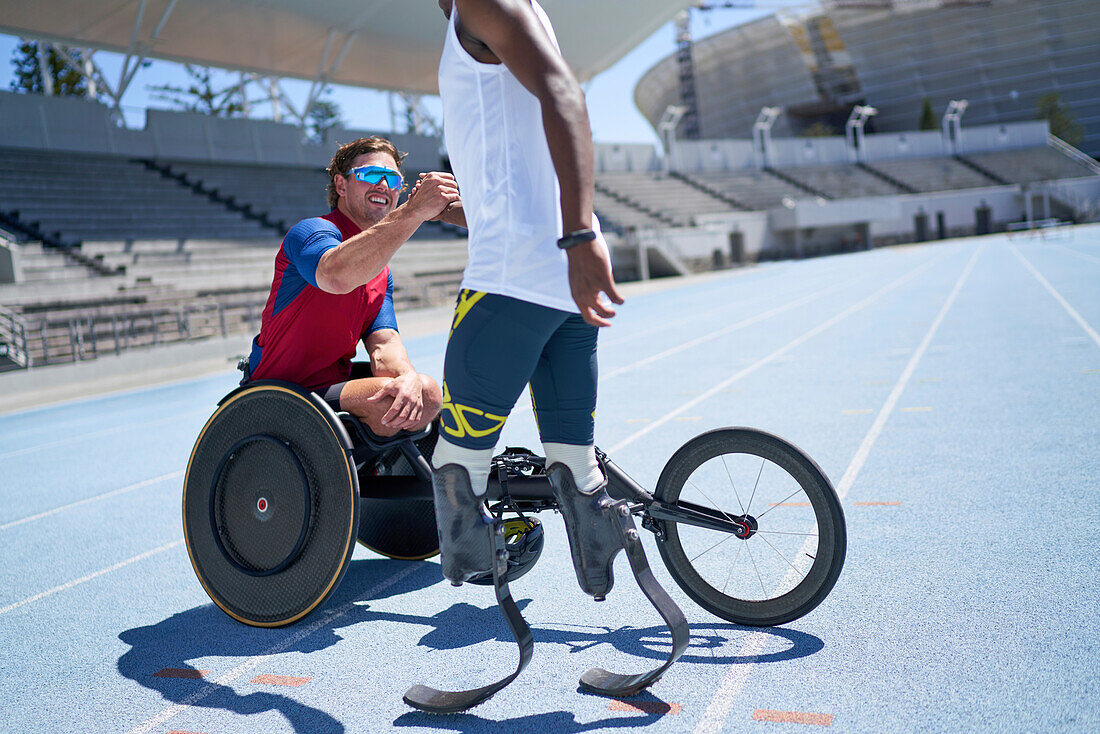 Male amputee and wheelchair athletes shaking hands