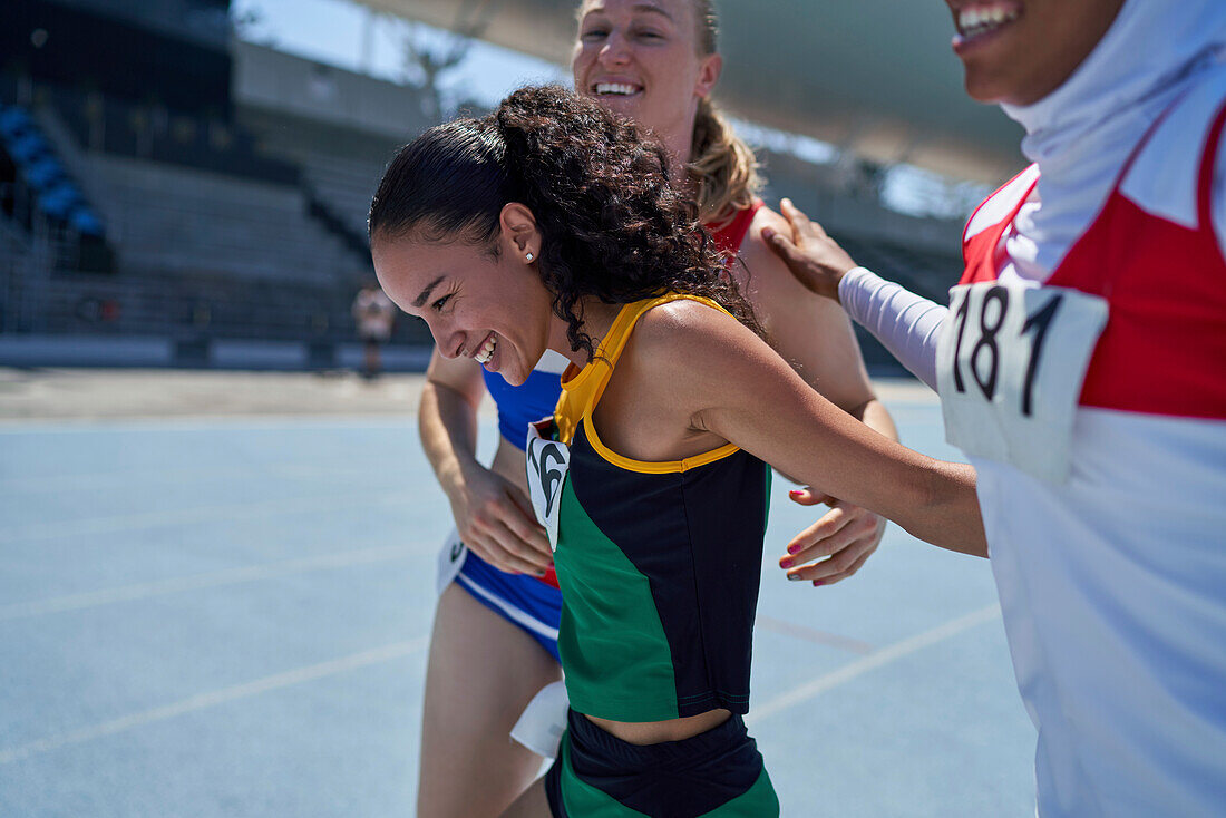 Happy female track and field athletes celebrating on track