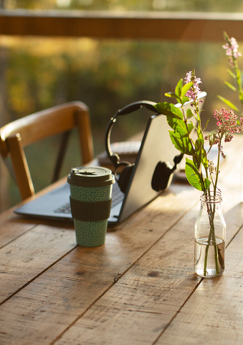 Laptop, coffee and simple wildflower bouquet on cafe table
