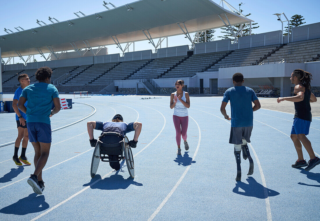Young athletes warming up on sunny blue stadium sports track