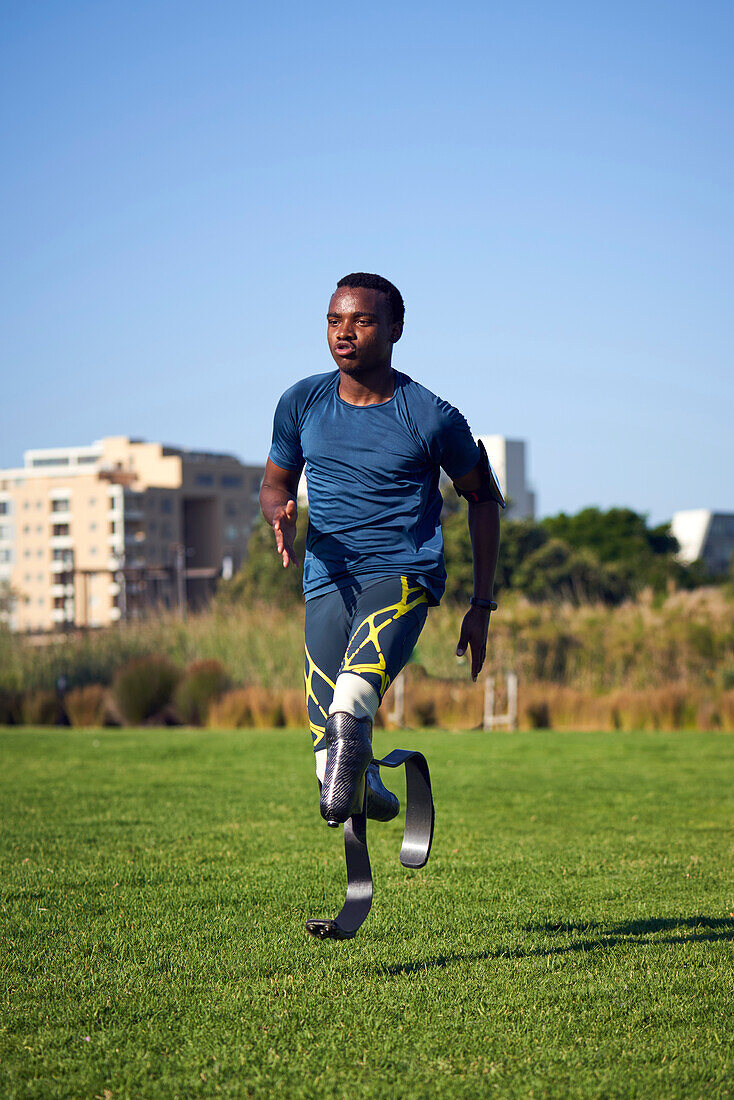 Focused young male amputee sprinter practicing in grass