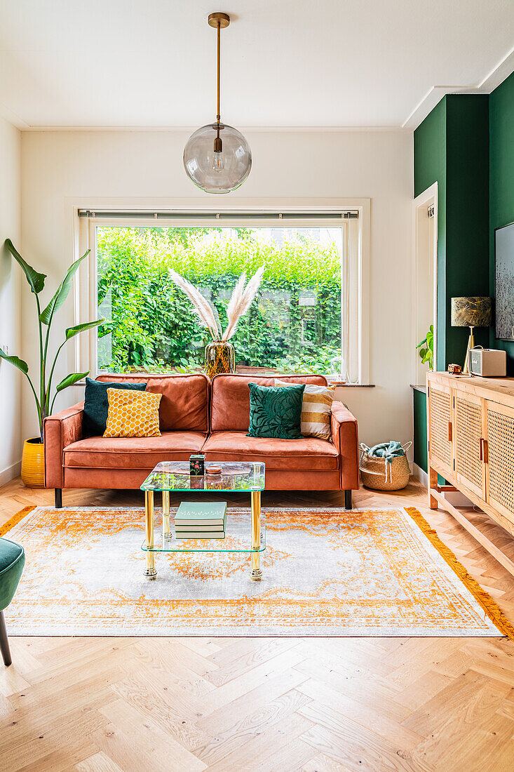 Brown leather sofa in front of large window in Bohemian living room