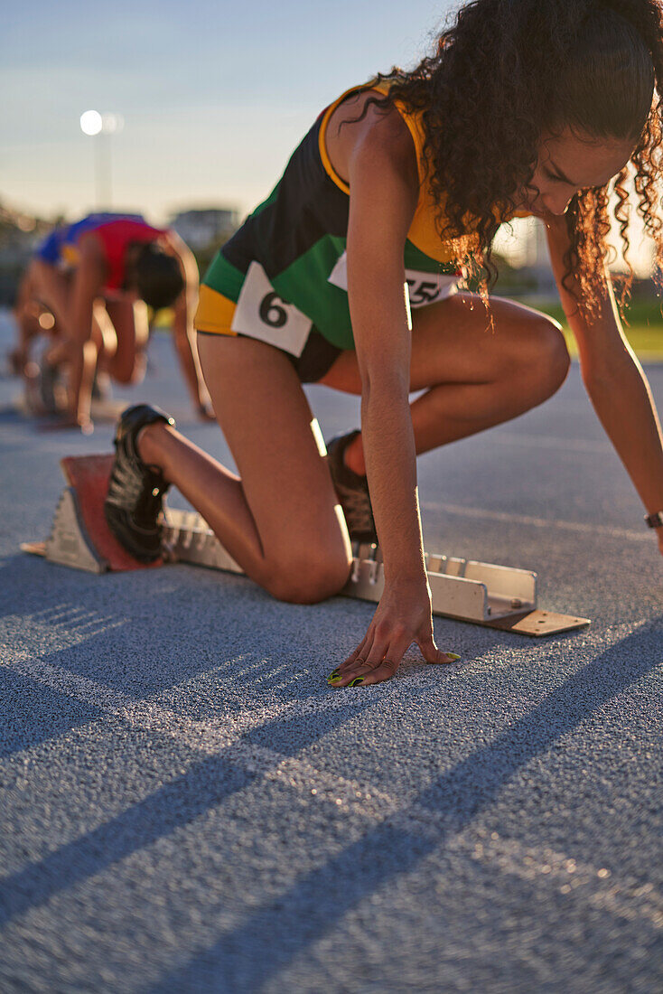 Female athlete preparing at starting block on track