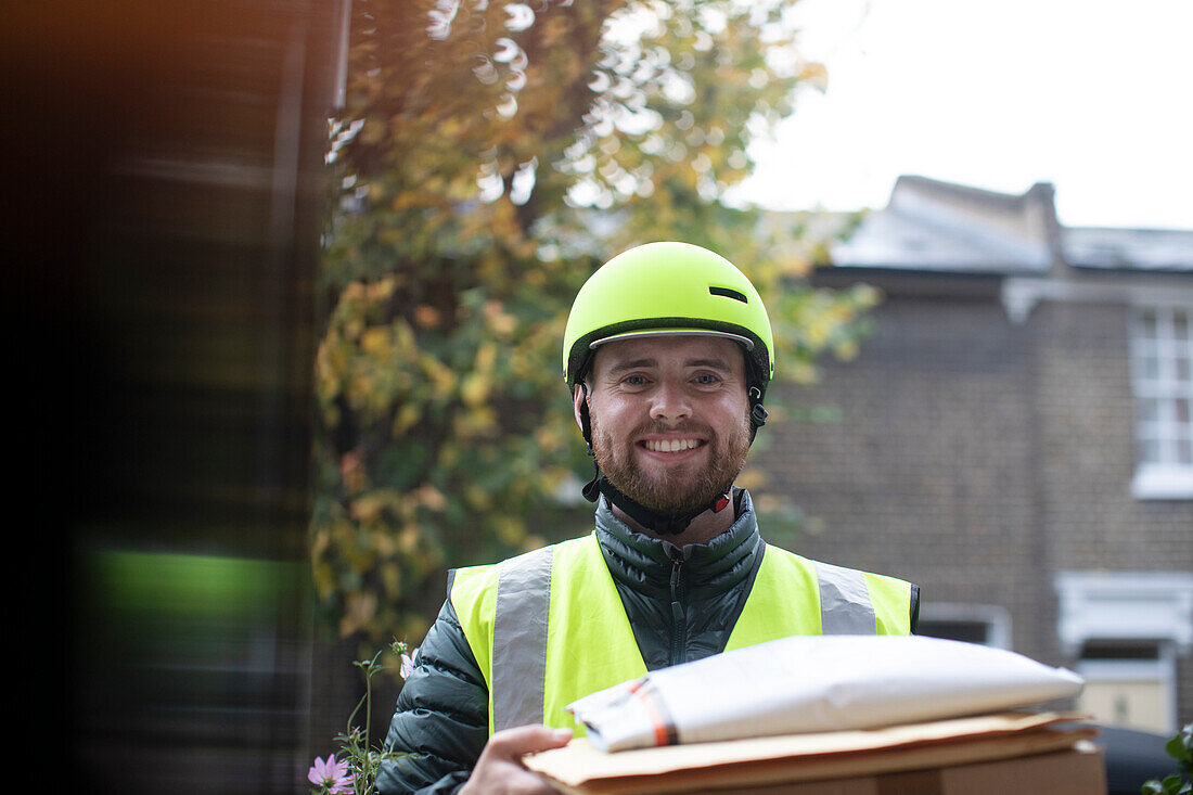 Friendly delivery man in helmet delivering packages at door