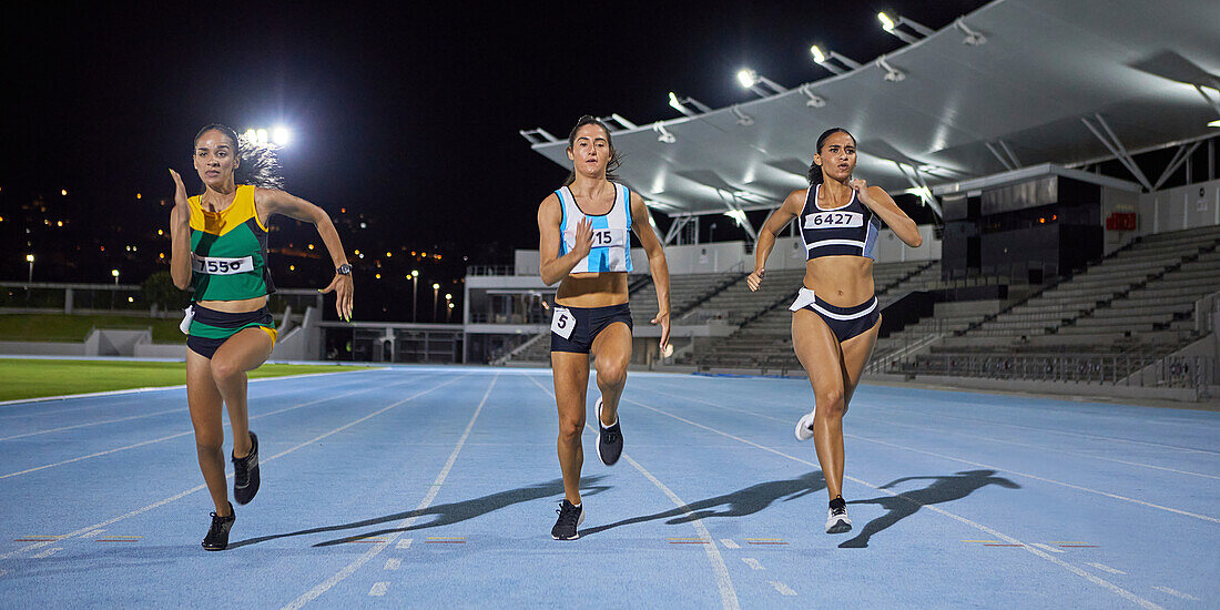 Female athletes running in competition on night track