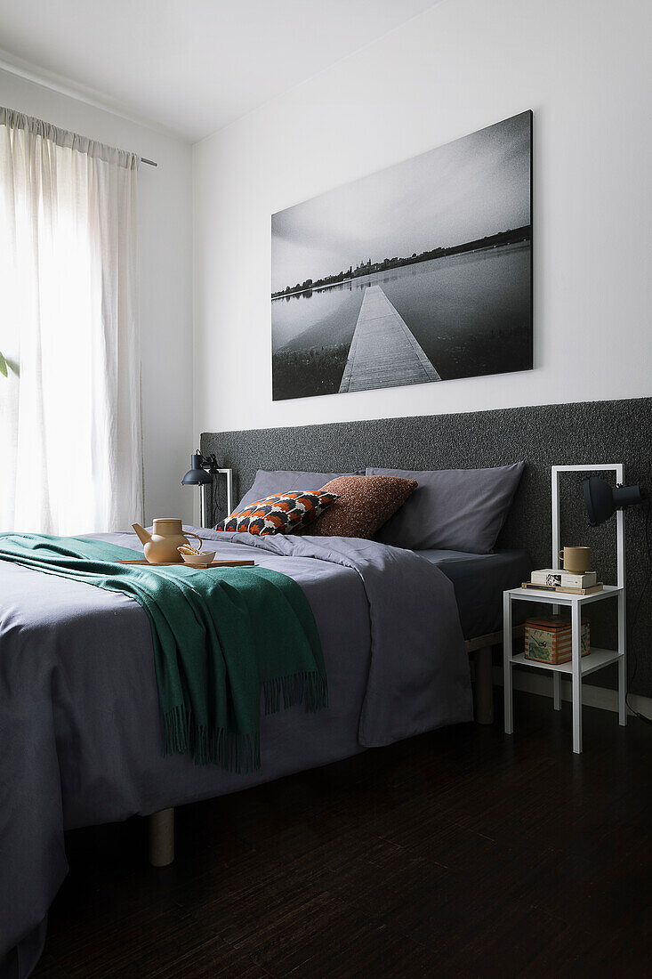 Doppelbett mit anthrazitfarbenem Betthaupt, darüber Landschaftsfoto