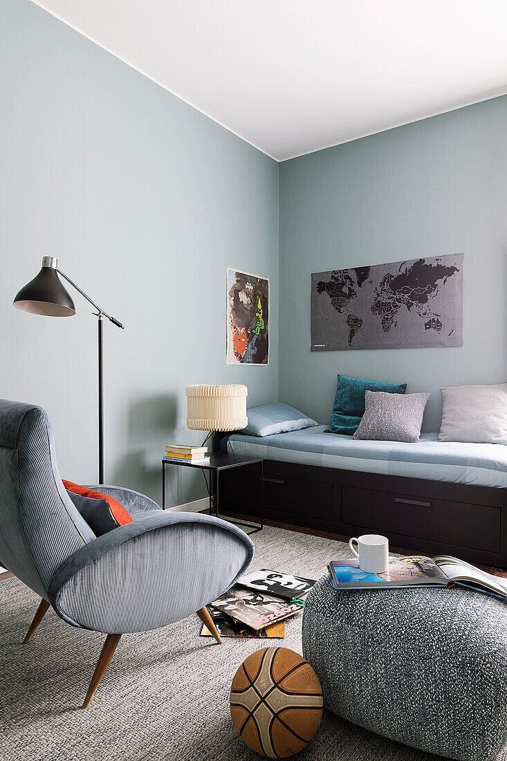 Bed, armchair and pouffe in teenager's bedroom with blue walls