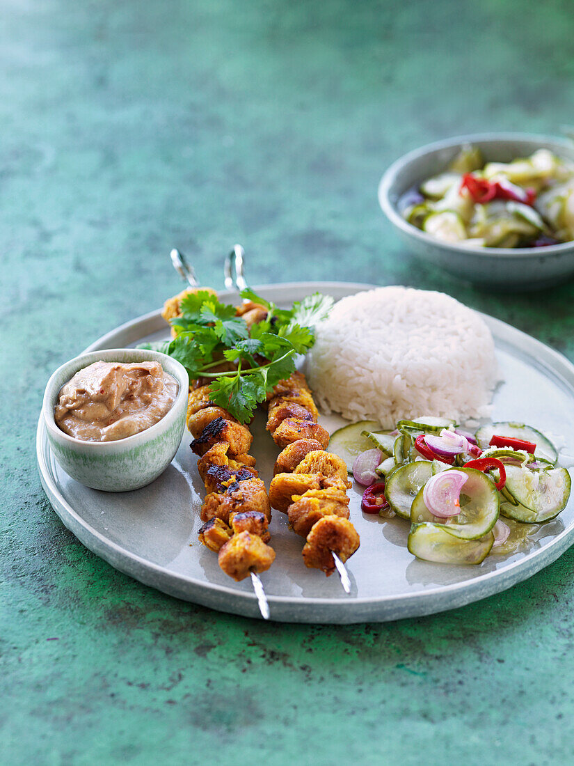 Skewers with grilled vegetarian bites, peanutsauce, coriander, rice, sidesalad with cucumber, chili and onion