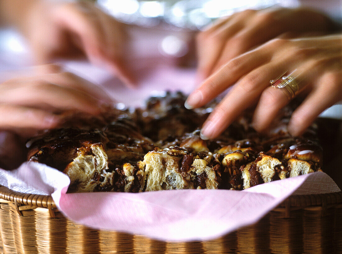Hands sharing pull apart bread with nuts
