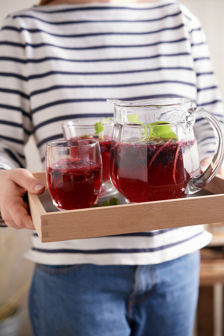 Frau serviert schwedische Blaubeerlimonade auf Tablett