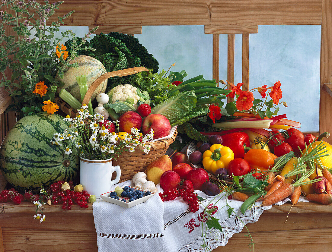 Stilleben mit Gemüse, Obst und Kräutern auf einer Holzbank