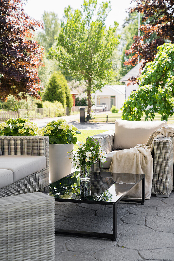 Rattanmöbel mit schwarzem Tisch auf der Terrasse