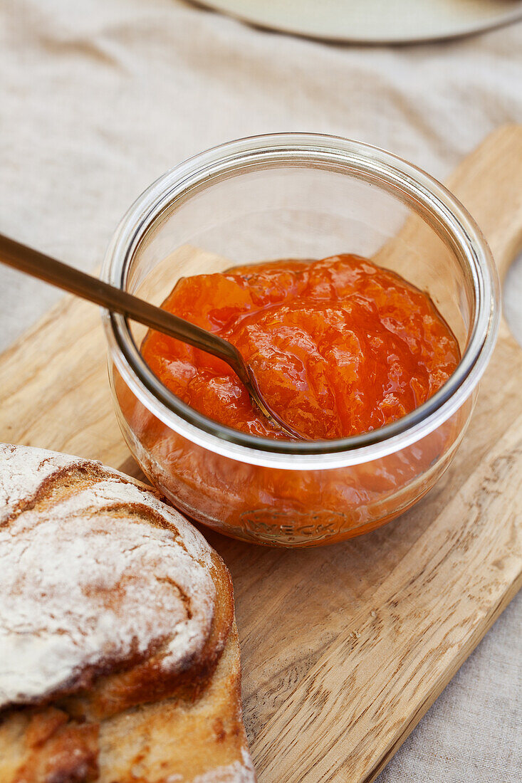 Homemade apricot jam and fresh bread on wooden board