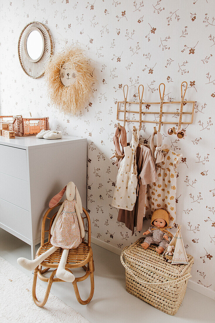 Garderobe mit Mädchenkleidung, Spielsachen und Kommode im Kinderzimmer mit Tapete