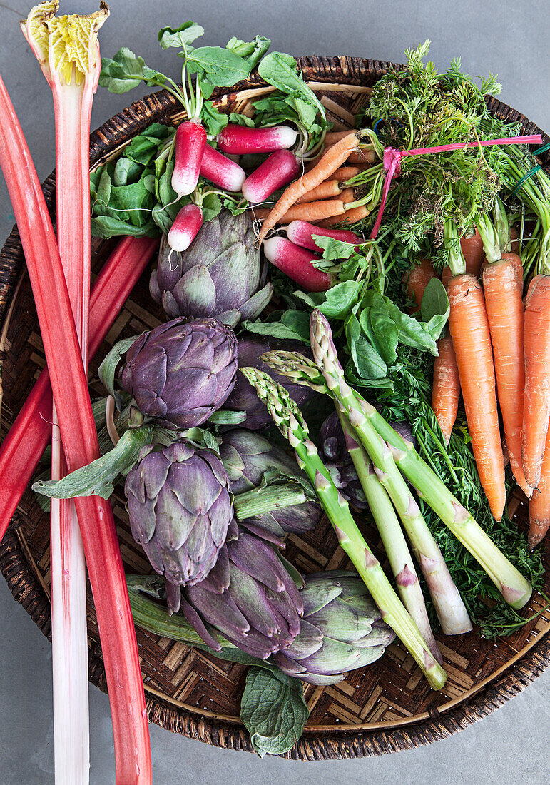 Korb mit frischem Gemüse: Rhabarber, Artischocken, Spargel, Karotten, Rettich