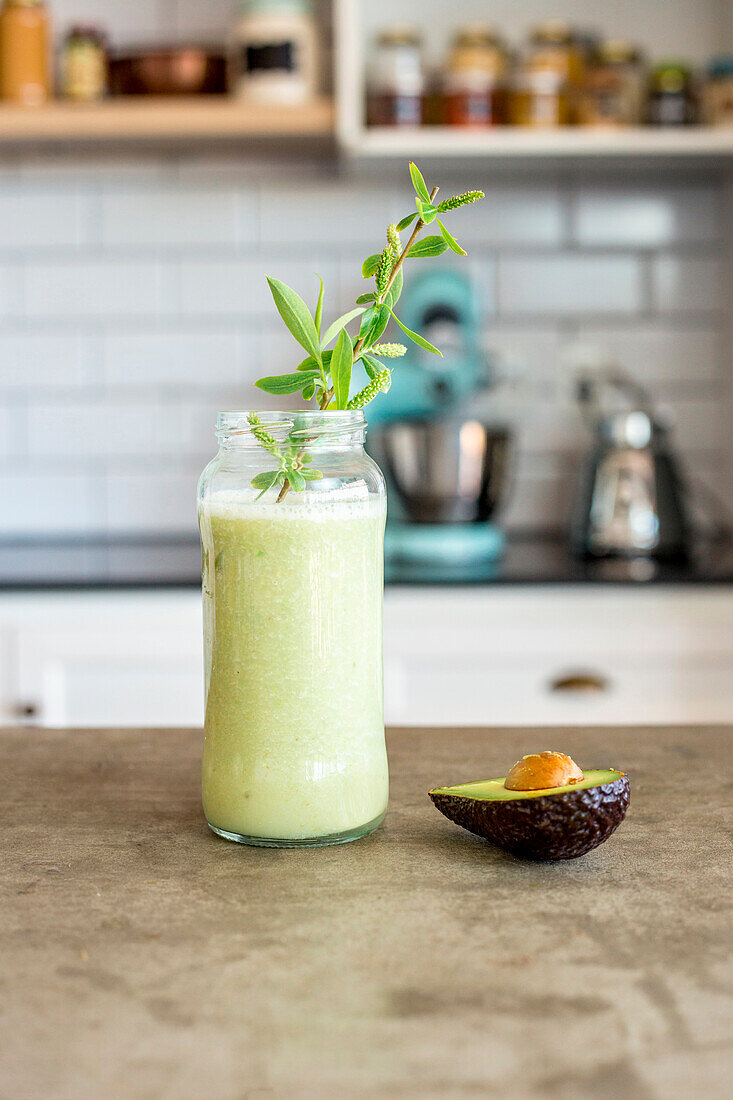 Avocado smoothie in a screw top glass on a kitchen table
