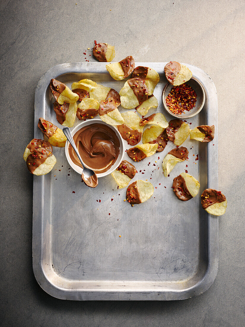 Potato chips with chilli flakes and chocolate icing on a tray