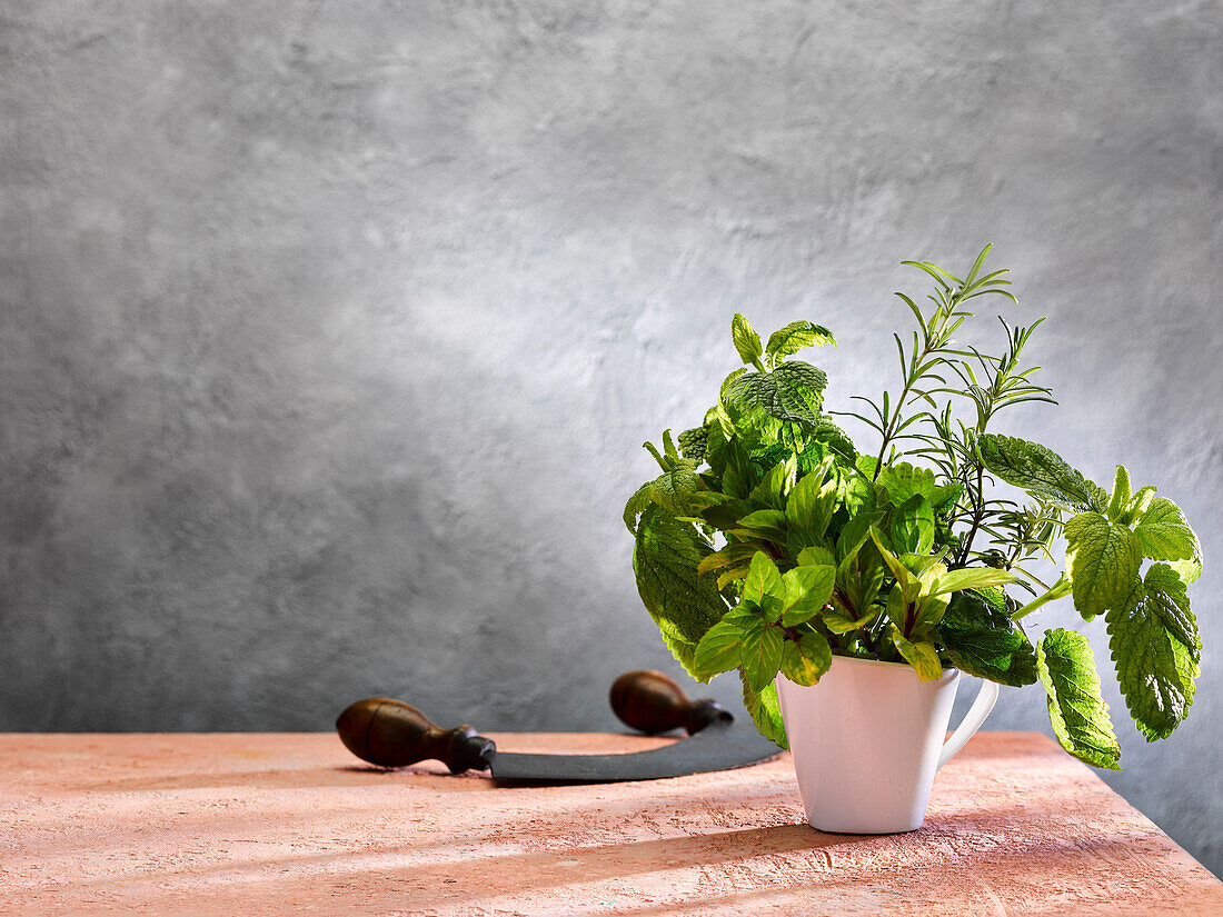 Fresh herbs in a cup next to a chopping knife