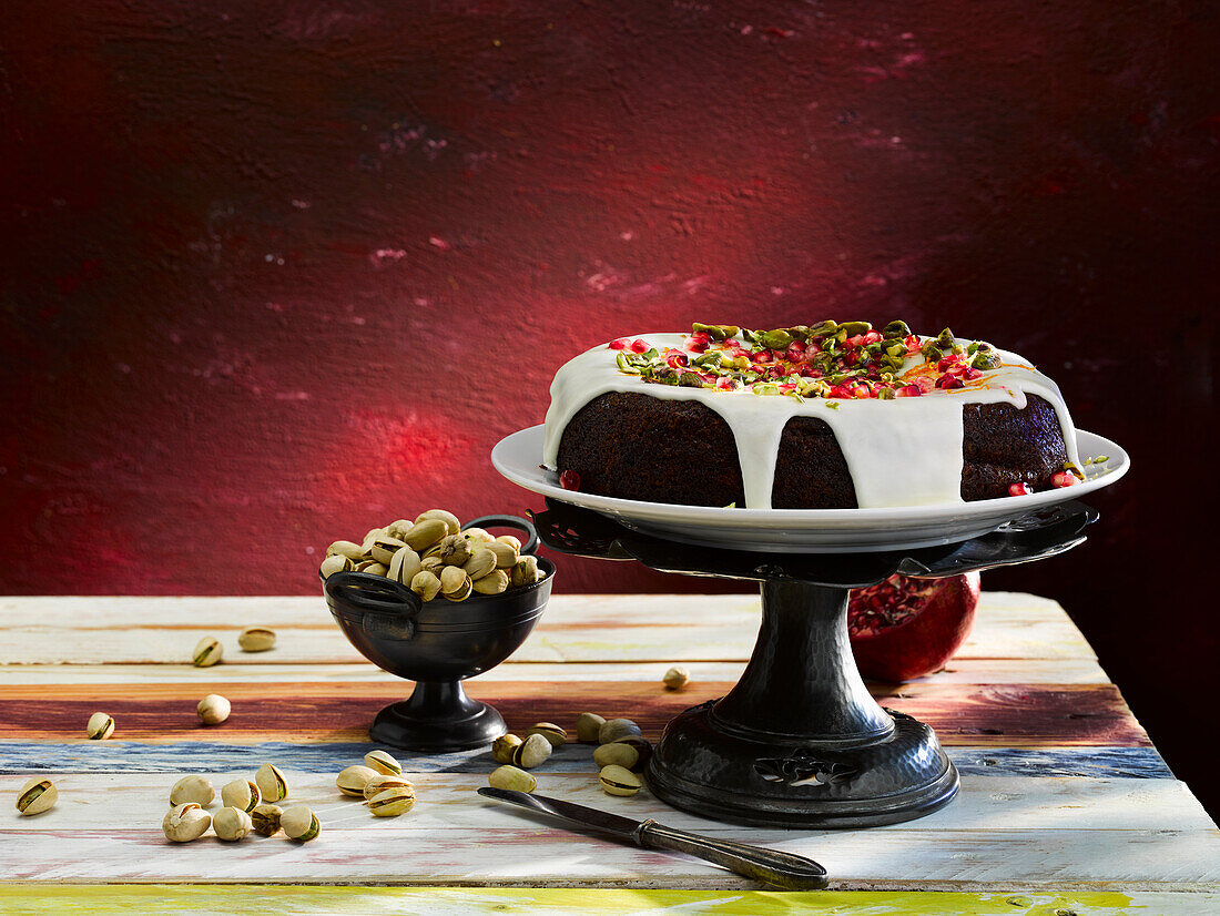 Vegan ginger molasses cake with sugar icing, pistachios and pomegranate seeds
