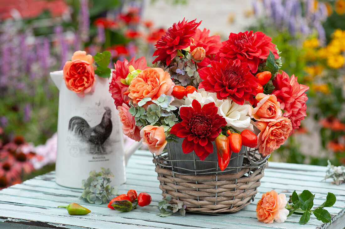 Bouquet of dahlias, rose petals, hydrangea flowers and ornamental pepper 'Salsa' in a basket