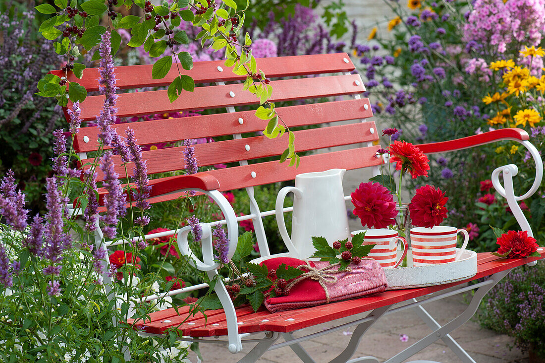 Red bench with dahlia flowers and tray with cups and jug