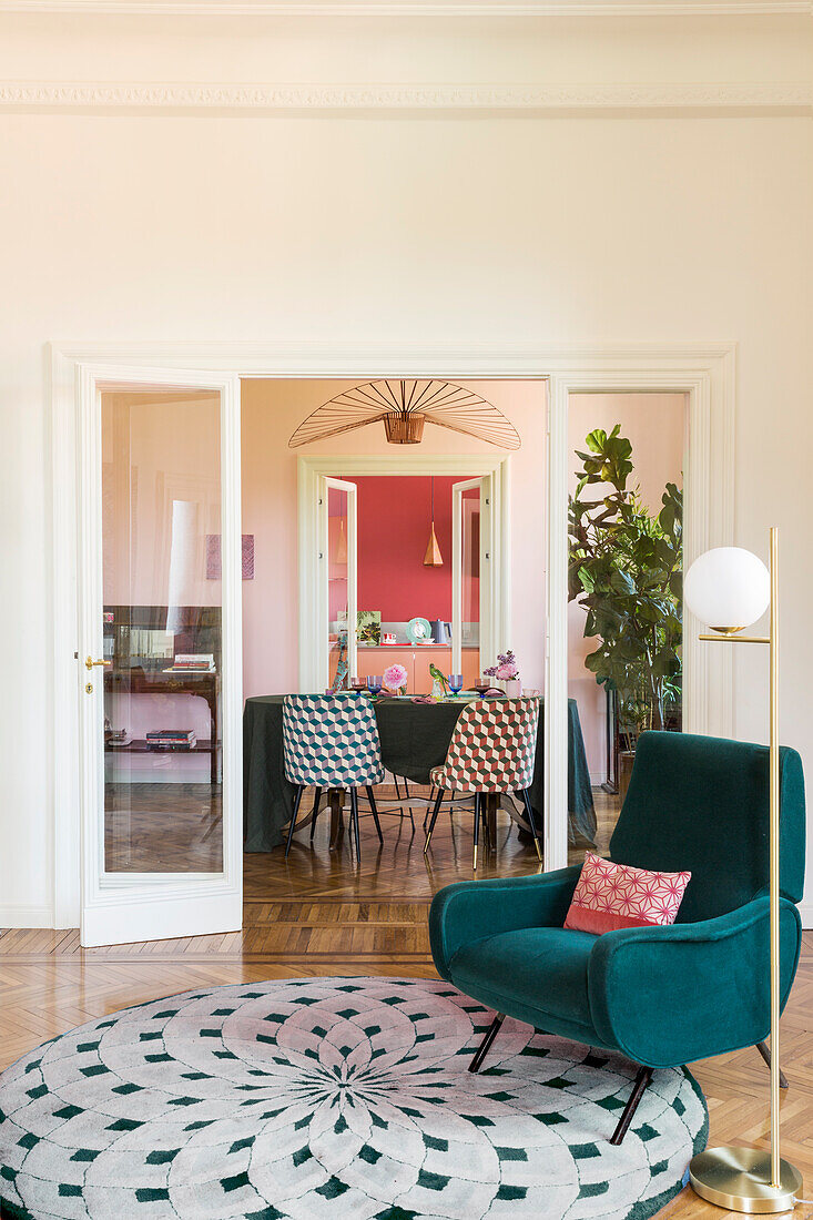 Green armchair and round rug in front of glass French doors with view into dining room