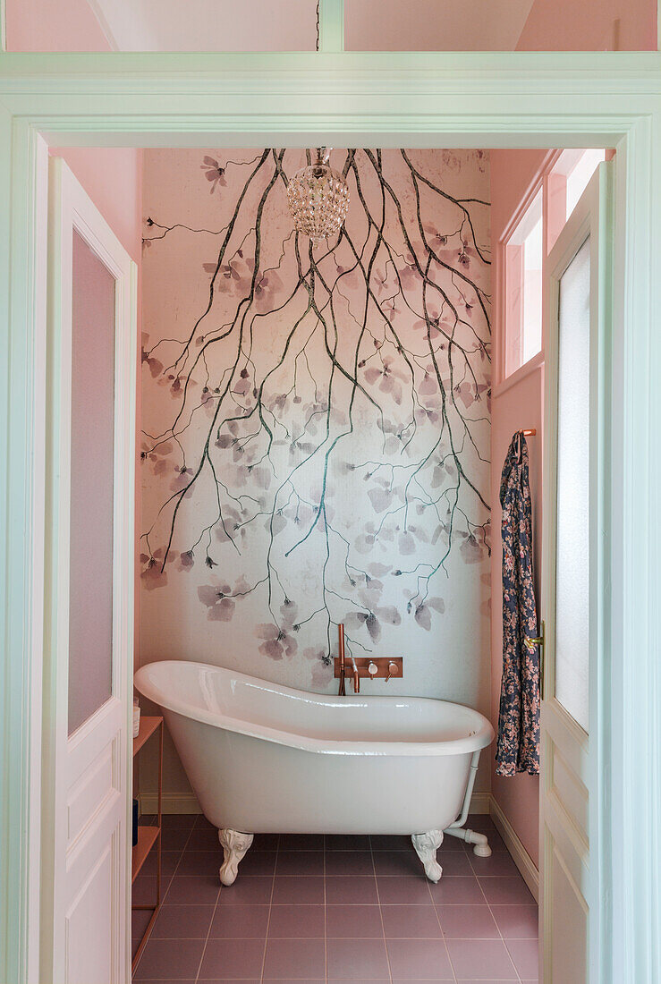 Freestanding vintage bathtub against photo wallpaper