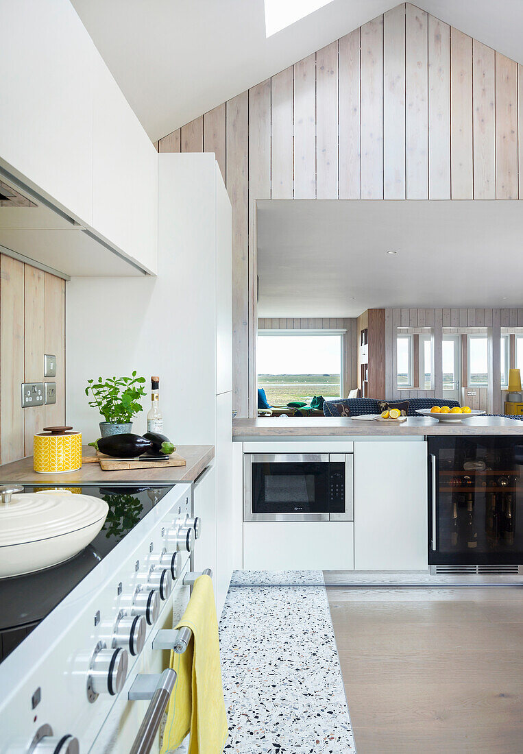 White fitted kitchen with counter in high-ceilinged room with skylight