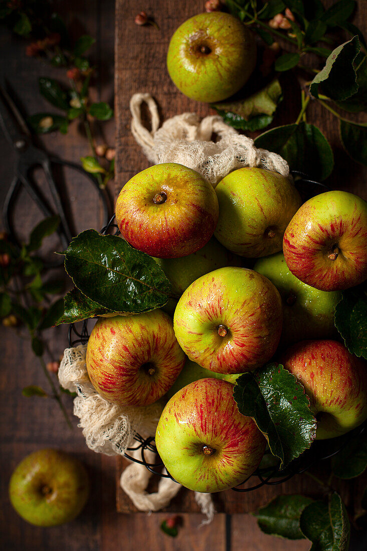 Apples in a wire bowl on a wooden board