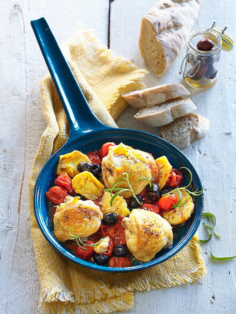 Hähnchenschenkel mit Tomaten, Artischocken und Oliven in einer Pfanne