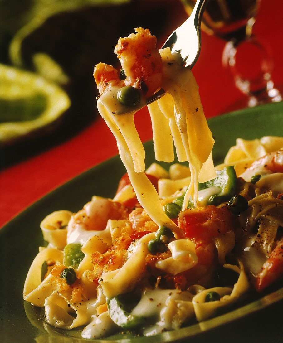 Ribbon noodles with shrimps, creamed vegetables on plate & fork
