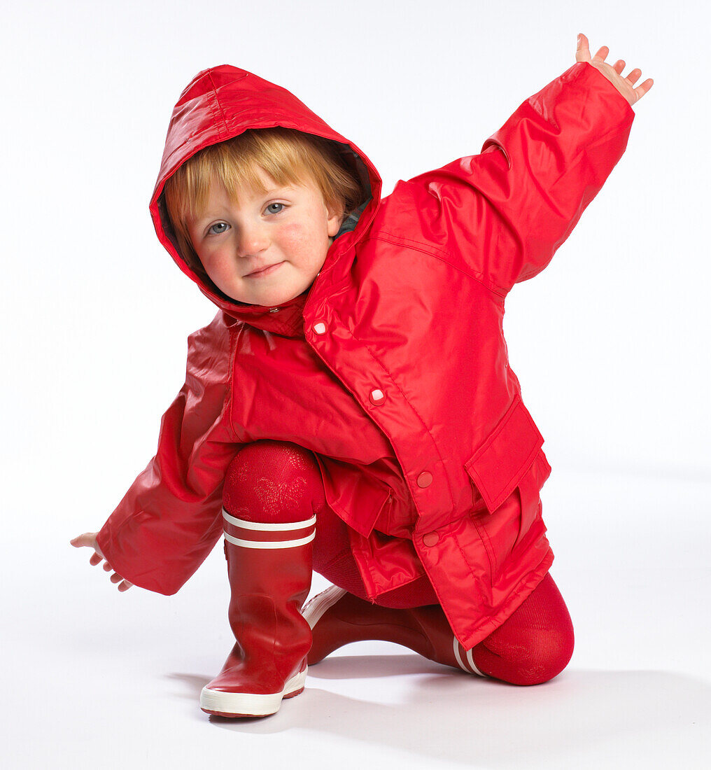 Toddler wearing red raincoat and wellington boots
