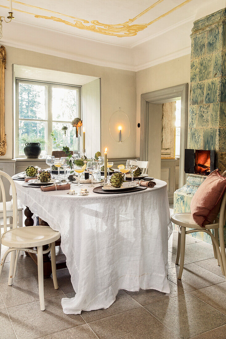 Festively laid table decorated with artichokes and cocktails in front of fireplace