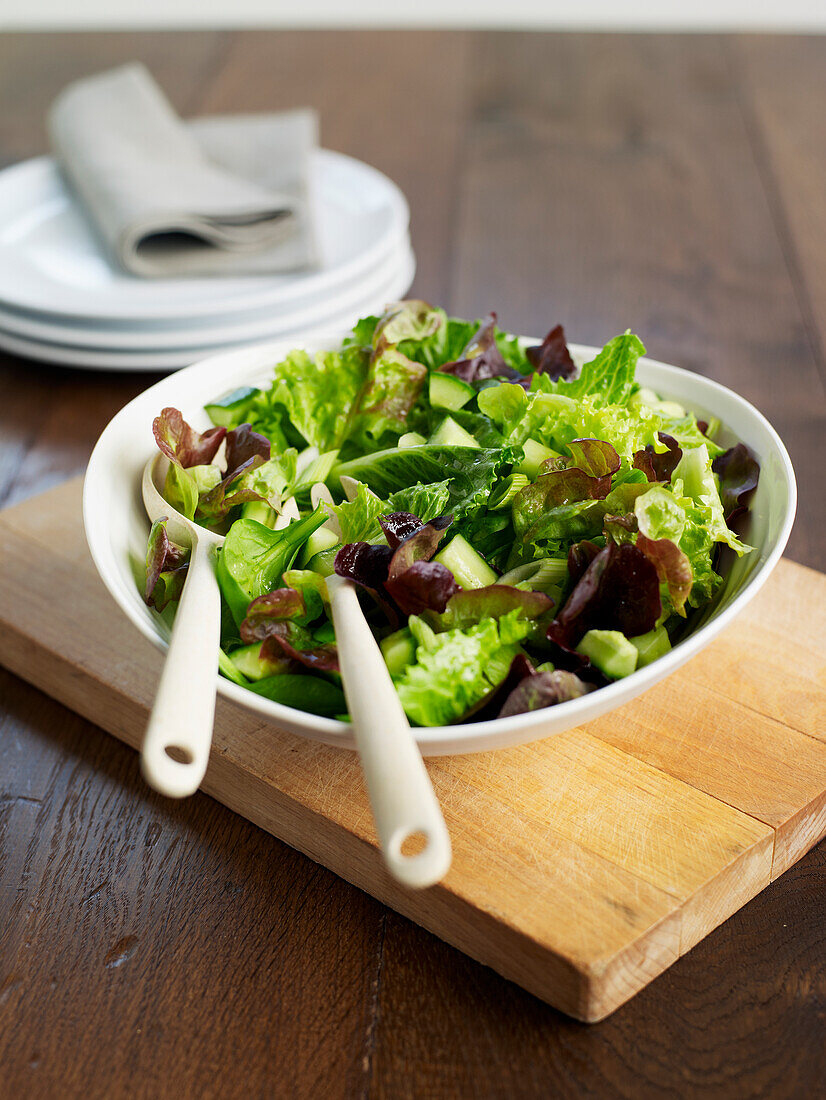 Green salad in bowl with salad servers