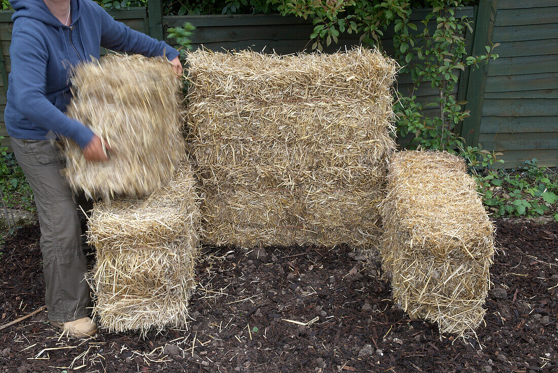 Woman making compost bin from bales of straw