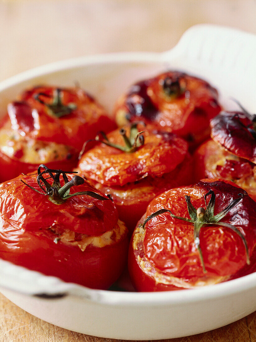 Six baked stuffed tomatoes in ceramic dish