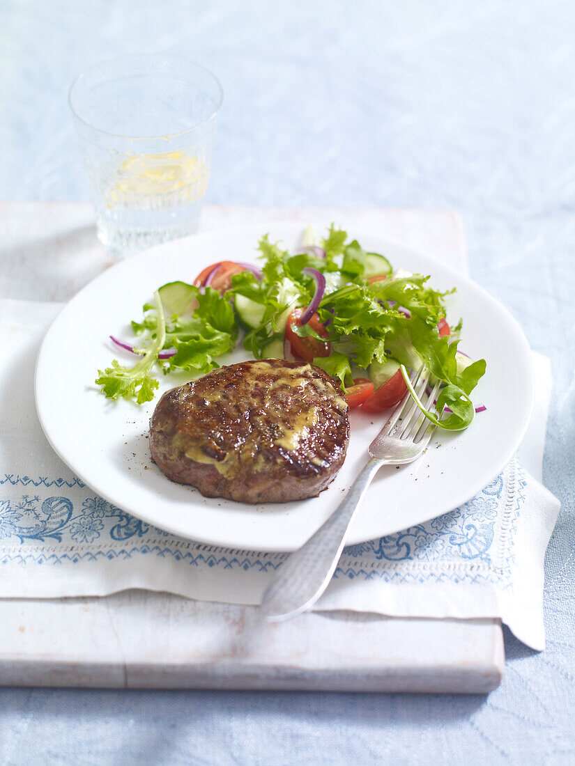 Steak topped with glazed mustard with salad